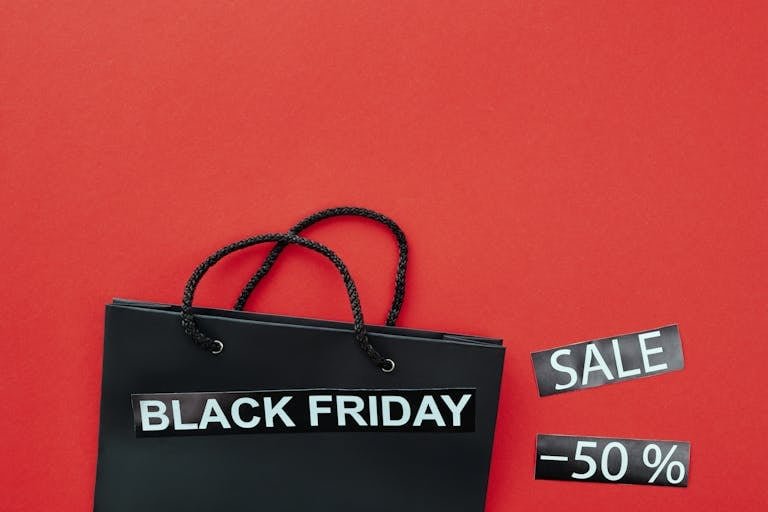 Black Friday shopping bag with sale tags on a vibrant red background.