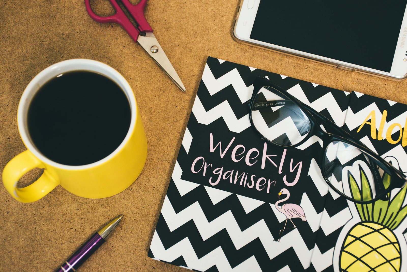 Flat lay of a workspace with coffee, notebook, smartphone, scissors, and pen for creativity.