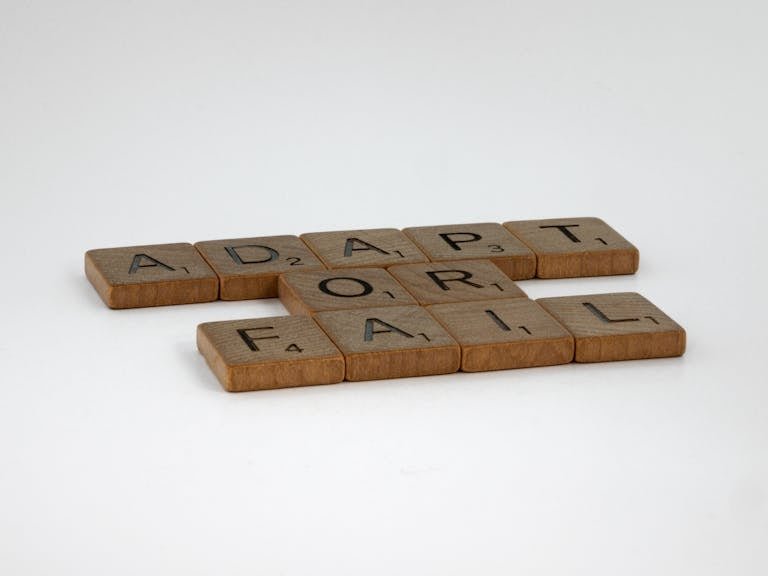 Scrabble tiles spelling 'Adapt or Fail' on a plain background, symbolizing decision-making.