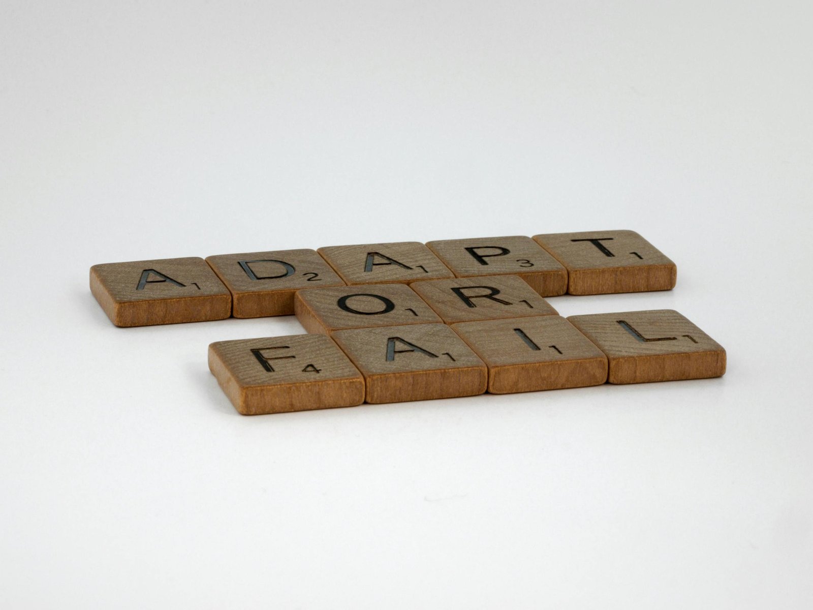 Scrabble tiles spelling 'Adapt or Fail' on a plain background, symbolizing decision-making.